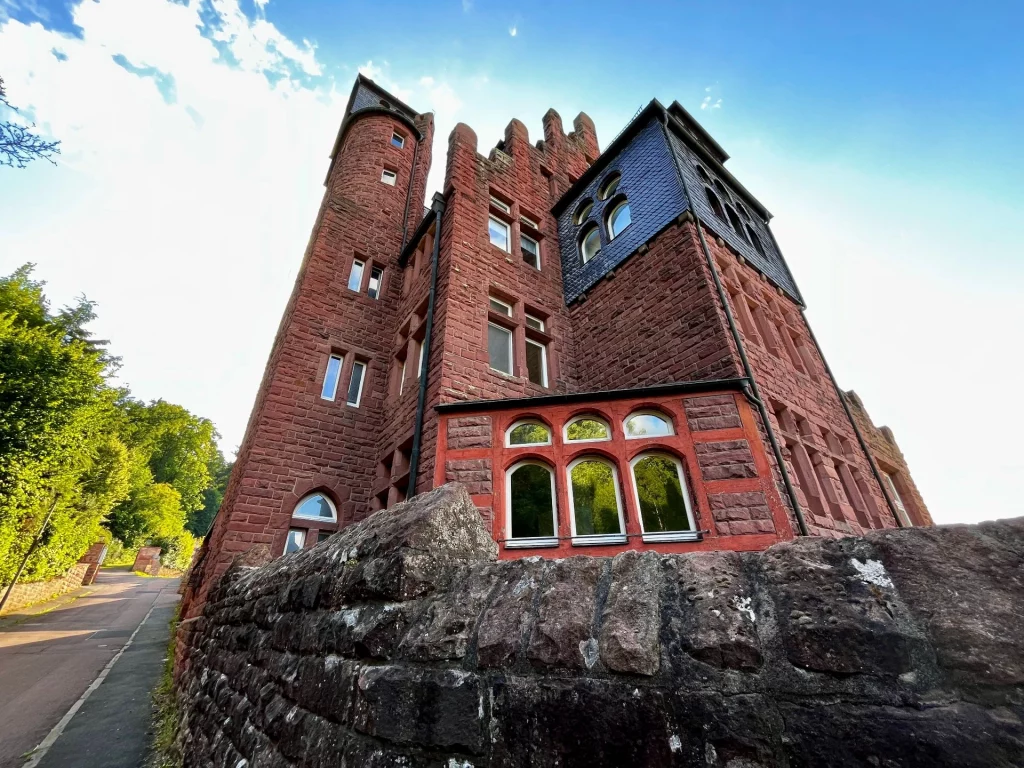 Burgfassade mit Türmen und Rundbogenfenstern. 