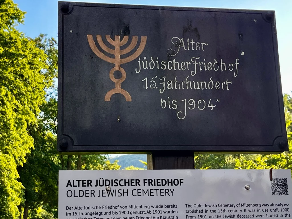 Informationstafel mit der Aufschrift ‚Alter jüdischer Friedhof, 15. Jahrhundert bis 1904‘ und Menora-Symbol. 