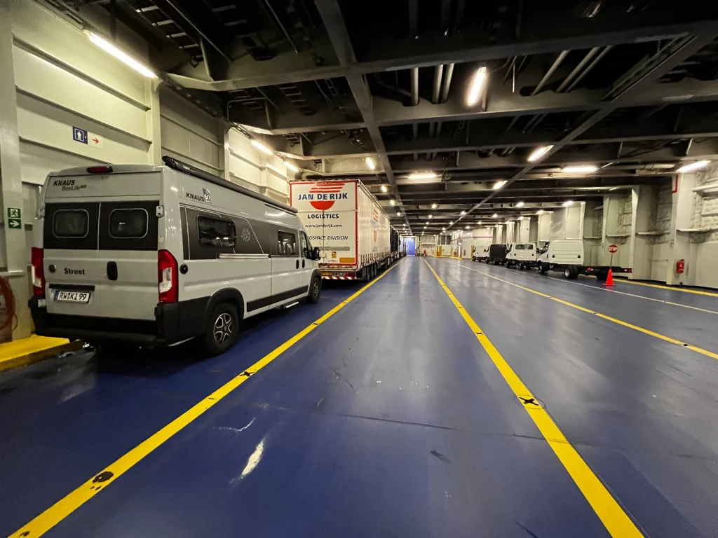 Ein Kastenwagen und ein LKW parken auf dem großräumigen, blau markierten Autodeck der Stena Line Fähre.