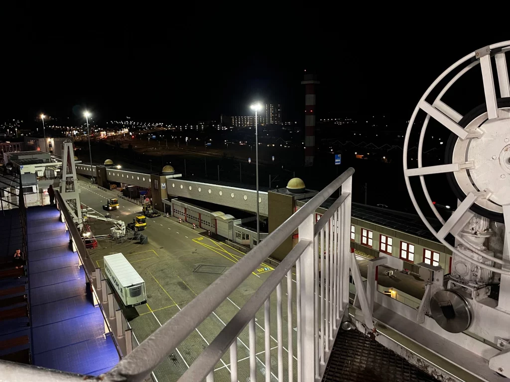 Nachtaufnahme vom Außendeck der Fähre auf die beleuchteten Hafenanlagen und Zufahrtsrampen von Hoek van Holland.