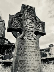 Ein detailliertes keltisches Hochkreuz aus Stein mit komplizierten Knotenmustern (Interlace) als Grabmal; die Inschrift erinnert an die Familie Townsley.