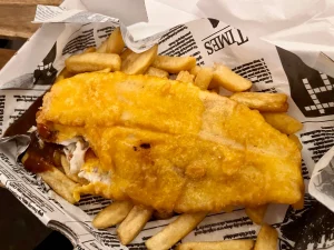 Traditionelle schottische Fish and Chips in Zeitungspapier, serviert als Reiseproviant während eines Roadtrips am Loch Lomond.