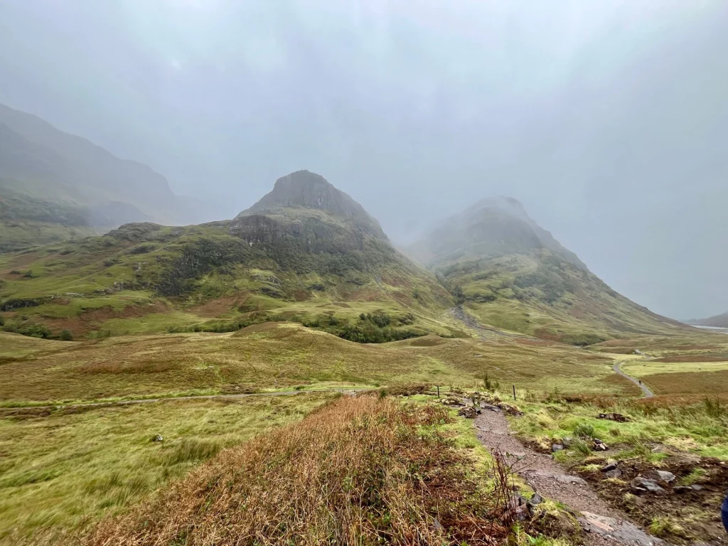 Eine nebelverhangene, grüne Bergkuppe in den schottischen Highlands unter einem grauen Wolkenhimmel.