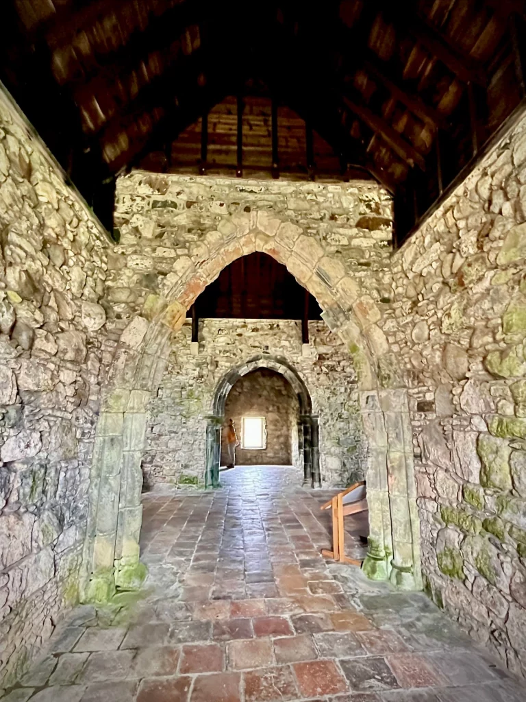 Die Innenansicht der Kapelle mit Blick durch zwei hintereinanderliegende gotische Steinbögen, die die verschiedenen Bereiche des historischen Kirchenbaus strukturieren.