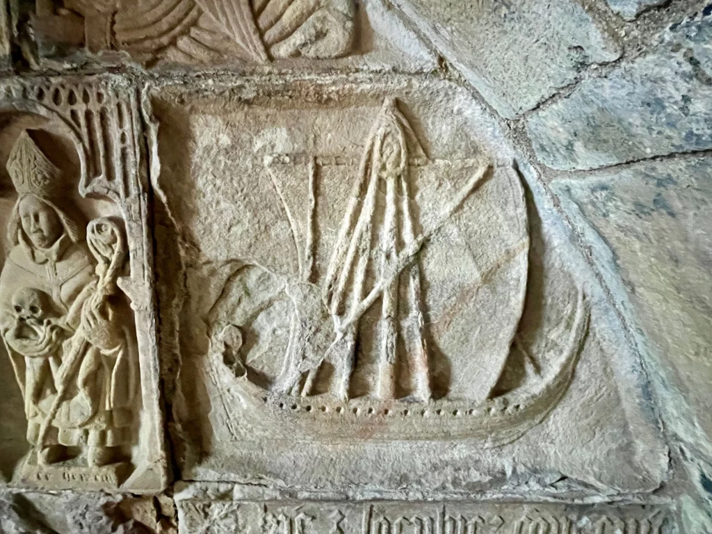 Detail eines Grabmonuments: Links ist ein Bischof mit Mitra und Stab zu sehen, rechts daneben eine Galeere (Birlinn) unter vollen Segeln – ein klassisches Symbol für die Macht der Insel-Clans.