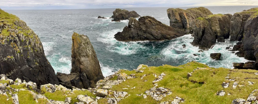 Spektakuläre Steilküste am Butt of Lewis. Dunkle, schroffe Felsformationen ragen aus dem aufgewühlten, türkisblauen Atlantik empor, während weiße Gischt gegen die Klippen schlägt.