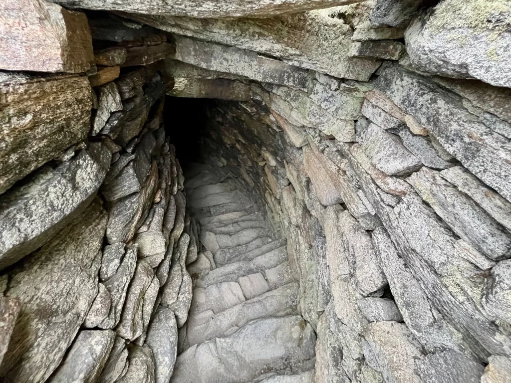 Blick in einen schmalen, steilen Treppenaufgang aus flachen Steinen, der tief in das Innere der doppelwandigen Broch-Mauer führt.