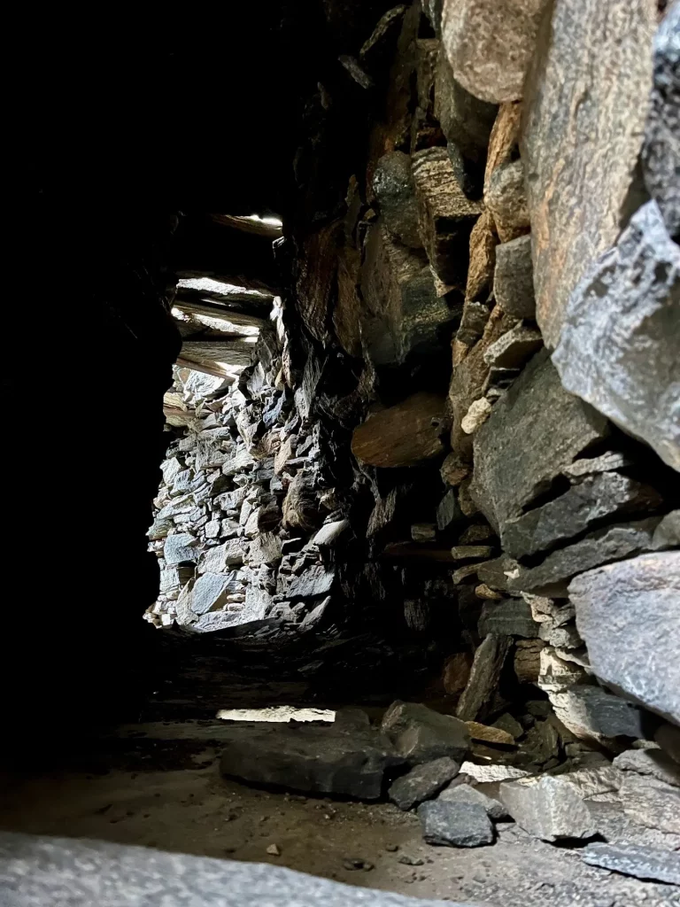Eine kontrastreiche Aufnahme aus dem Inneren der Mauergalerie. Das Licht fällt von oben durch die Steinritzen und beleuchtet die rauen, massiven Gesteinsschichten der inneren Konstruktion.