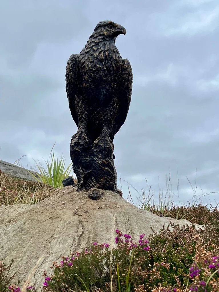 Dunkle Tierskulptur eines Adlers auf einem Felsen vor Hebriden-Kulisse, Kunsthandwerk beim Dun Carloway..