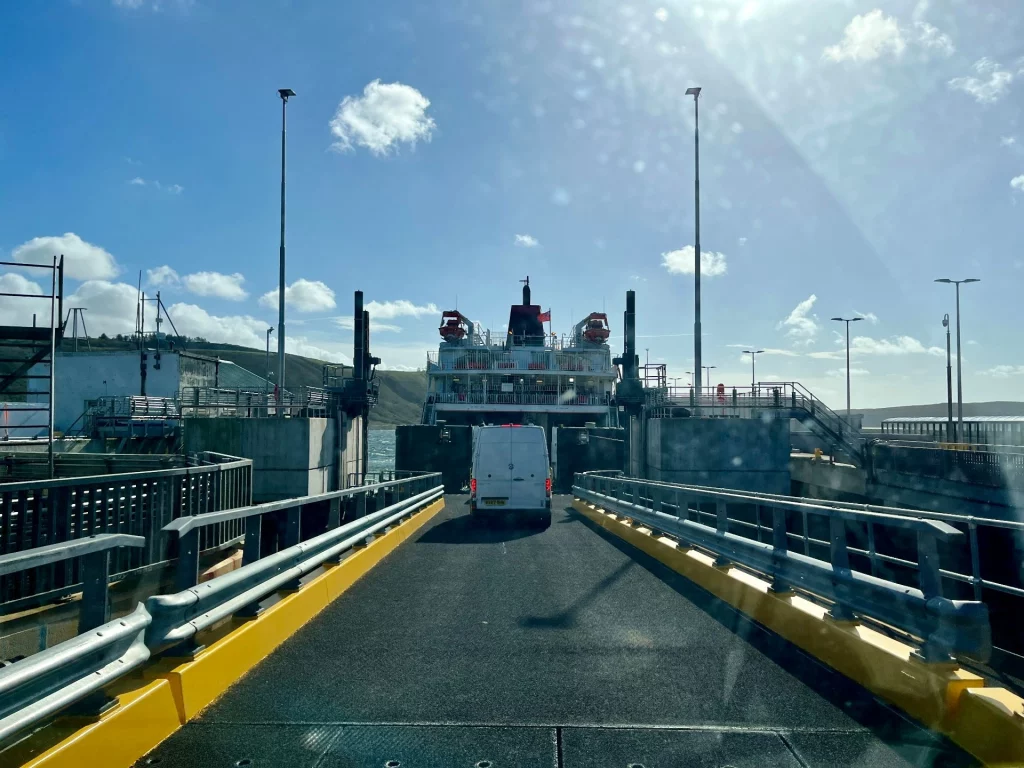 Blick aus der Windschutzscheibe eines Fahrzeugs (Kätter) auf die Auffahrrampe der Fähre, auf der ein weißer Transporter gerade an Bord fährt.