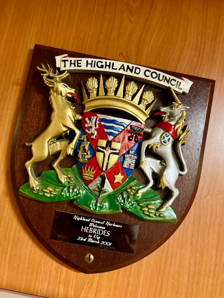 Ein hölzernes Wappenschild des „Highland Council“ mit der Aufschrift „Welcome to the Hebrides