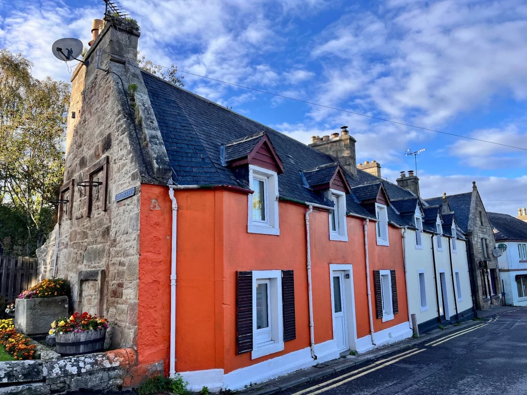 Eine Reihe charakteristischer schottischer Steinhäuser in Tain, eines davon in auffälligem Orange gestrichen.