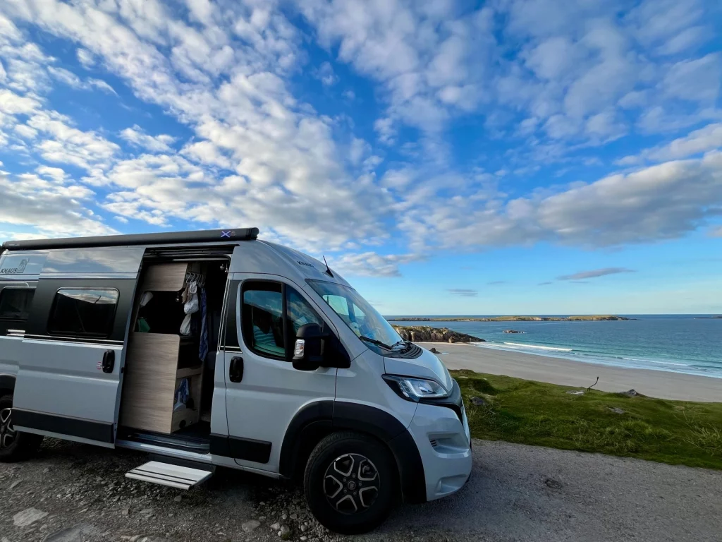 Hellgrauer Kastenwagen Camper mit offener Schiebetür auf einem Küstenstellplatz an der Sango Bay in Durness, Schottland.
