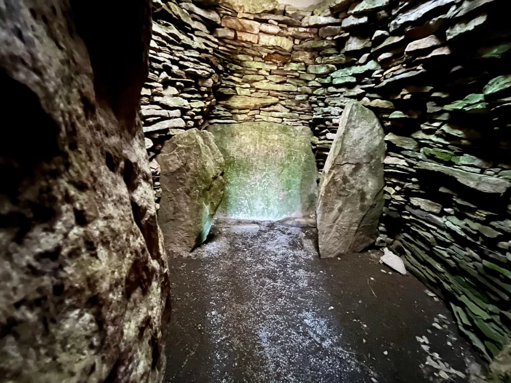 Innenaufnahme der Grabkammer mit Fokus auf die Moosbewachsenen Steinplatten und die präzise geschichteten Wände aus flachem Gestein.