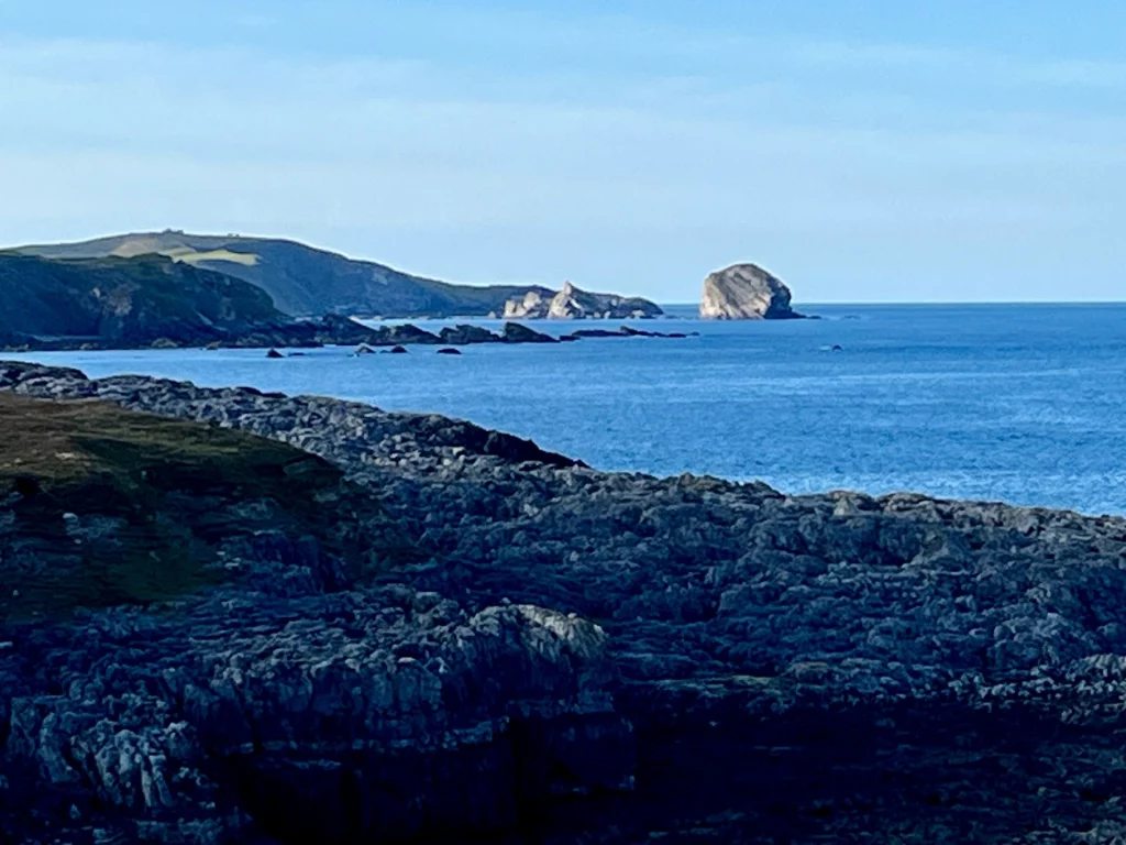 Schroffe dunkle Felsküste in Durness, Schottland, mit markanten Brandungspfeilern im Meer.