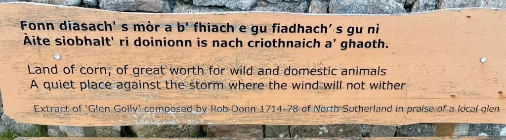 Holzsitzbank bei der Smoo Cave in Durness mit einer gälischen Inschrift und englischer Übersetzung des Gedichts Glen Golly von Rob Donn.
