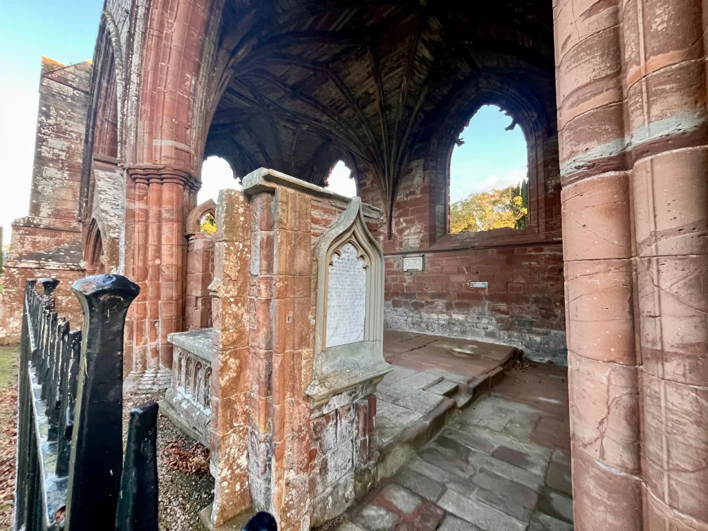 Innenansicht des Südgangs mit Blick auf das gotische Kreuzrippengewölbe und ein verziertes Wandmonument.
