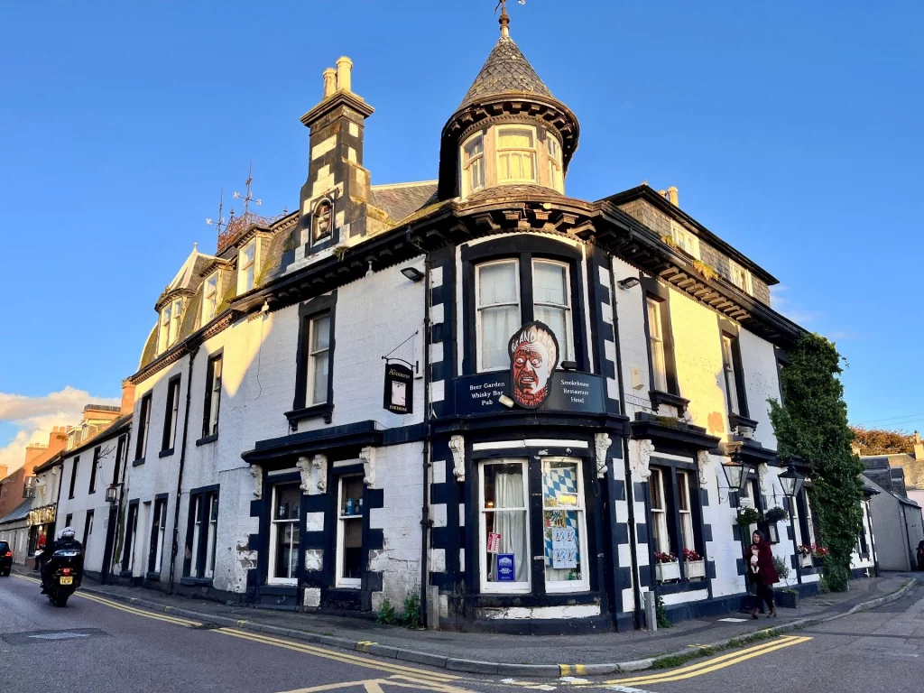 Ein markantes, schwarz-weißes Eckhaus in Tain mit einem runden Turmanbau, das als Pub und Hotel dient.