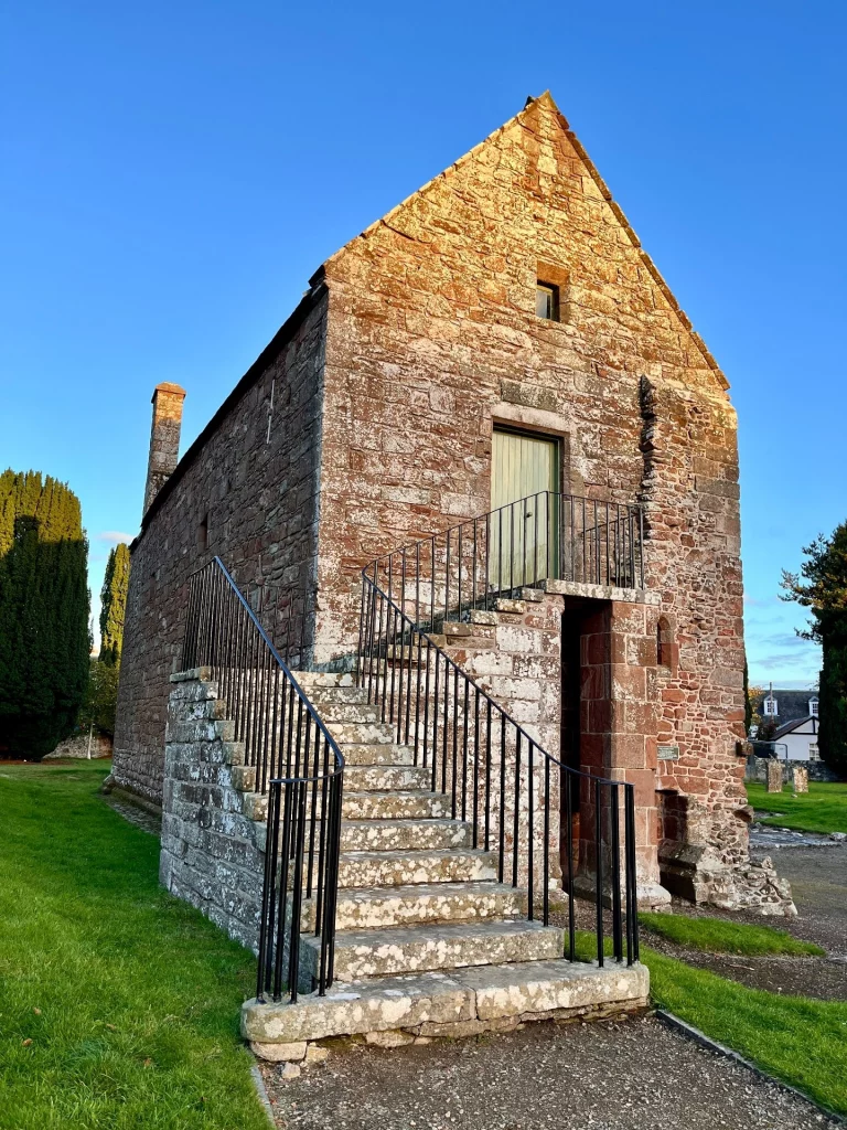Nahaufnahme des zweistöckigen Kapitelhauses aus rotem Sandstein mit einer markanten Außentreppe aus Stein.