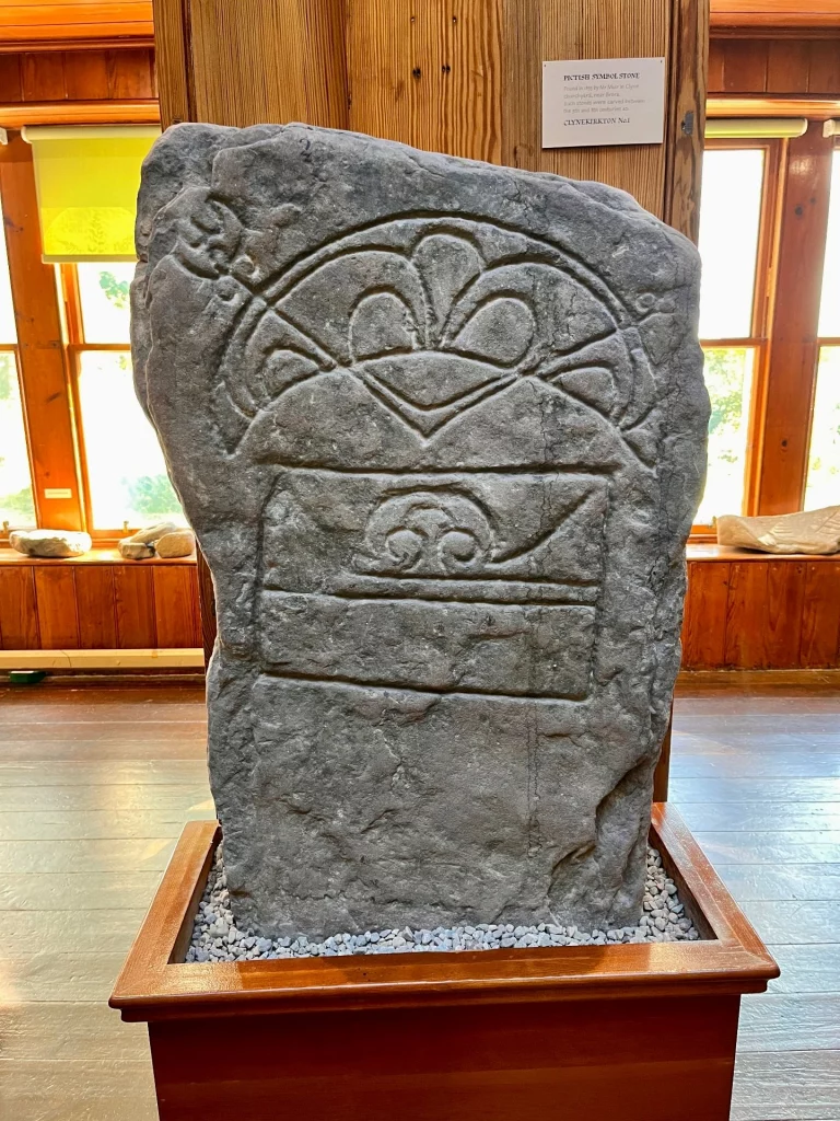 Ein verwitterter Stein mit dem piktischen Mondsichel-Symbol (Crescent) und einem sogenannten V-Stab.