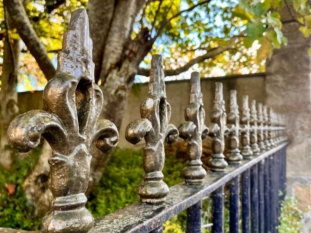 Nahaufnahme eines historischen, schmiedeeisernen Zauns mit Lilien-Verzierungen (Fleur-de-Lis) in Tain.