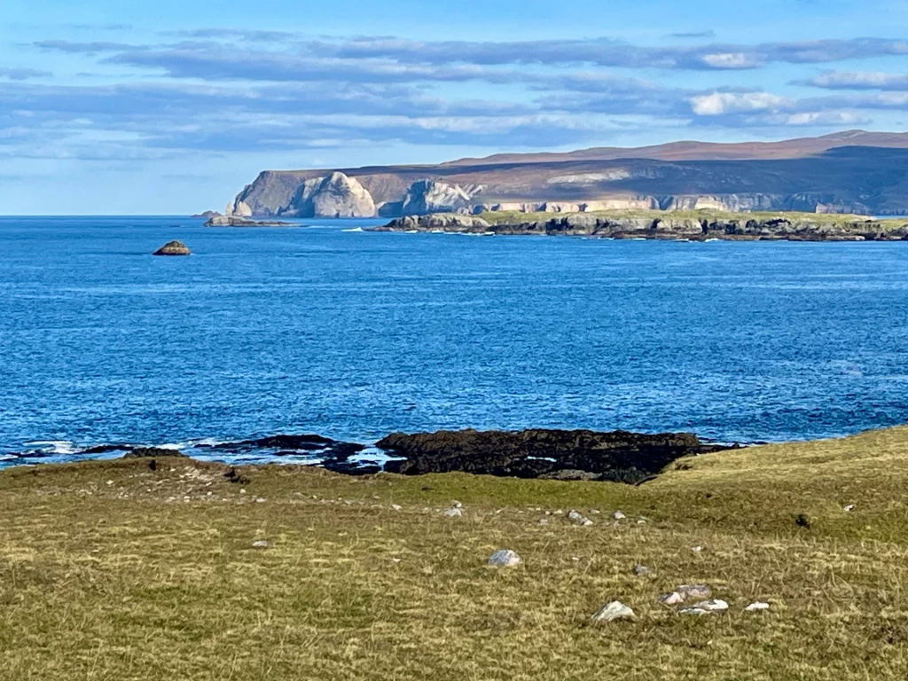 Panorama der schottischen Küste bei Durness mit Blick auf die Klippen von Faraid Head unter blauem Himmel.