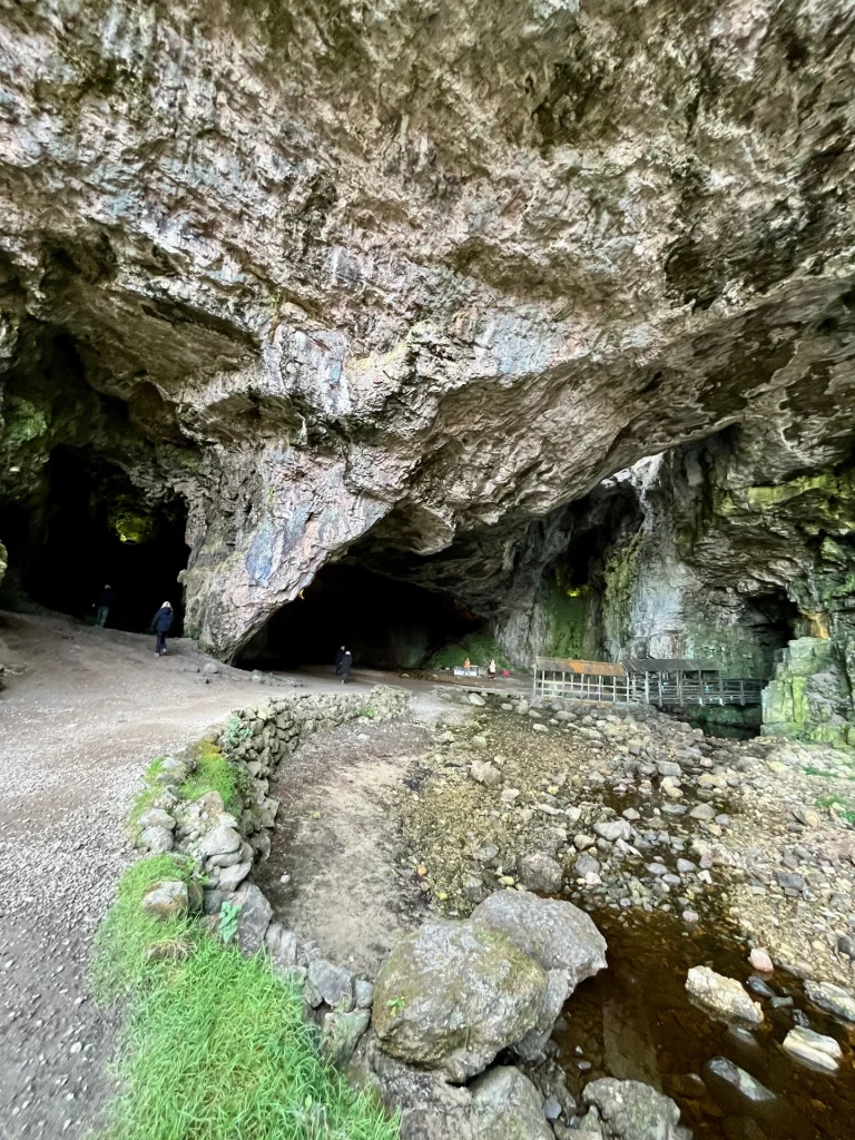 Blick von einem geschwungenen Pfad aus auf die gigantische Deckenkonstruktion der Höhle und den hölzernen Steg, der tiefer in den Fels führt.