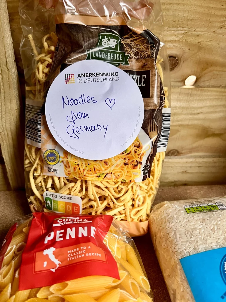 Eine Packung Landfreude Spätzle steht in einem Regal. Auf der Packung klebt ein handgeschriebener Zettel mit der Aufschrift „Noodles from Germany“ und einem kleinen Herz.