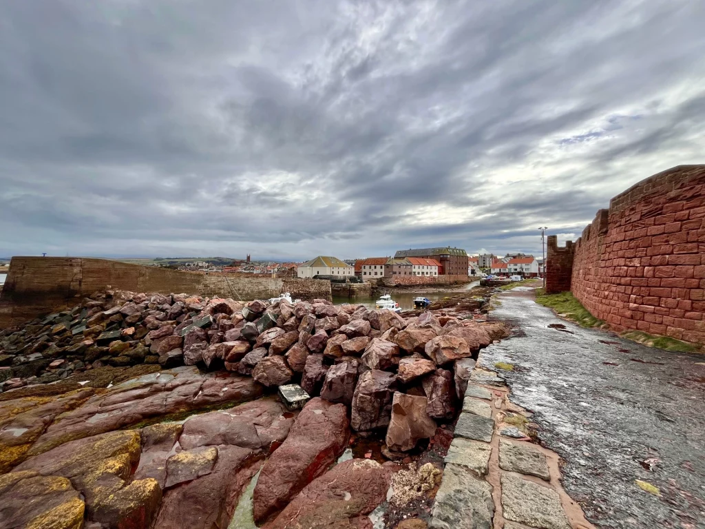 Weite Ansicht der felsigen Küstenlandschaft von Dunbar bei Ebbe unter einem bewölkten Himmel.