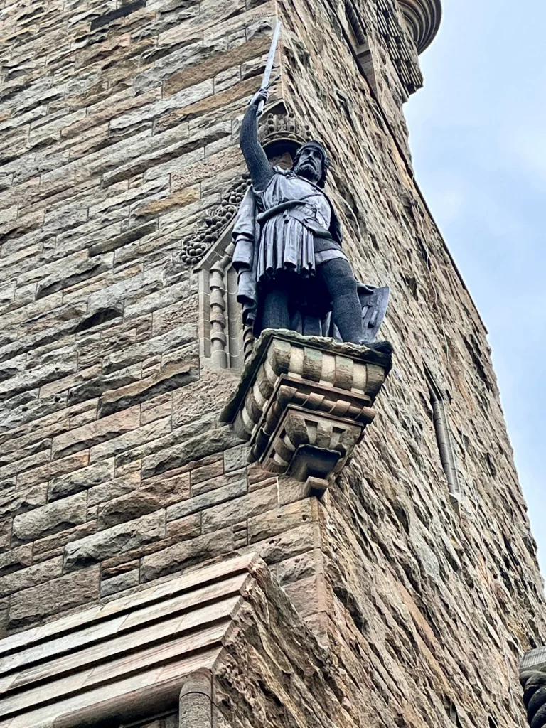 Detailaufnahme der Bronzestatue von William Wallace an der Fassade des National Wallace Monument in Stirling.