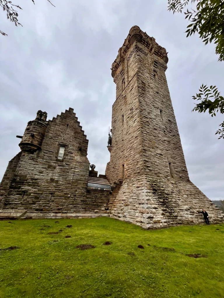 Rückansicht des Wallace Monument Turms von einer grünen Wiese aus gesehen, die die massive Steinbauweise zeigt.