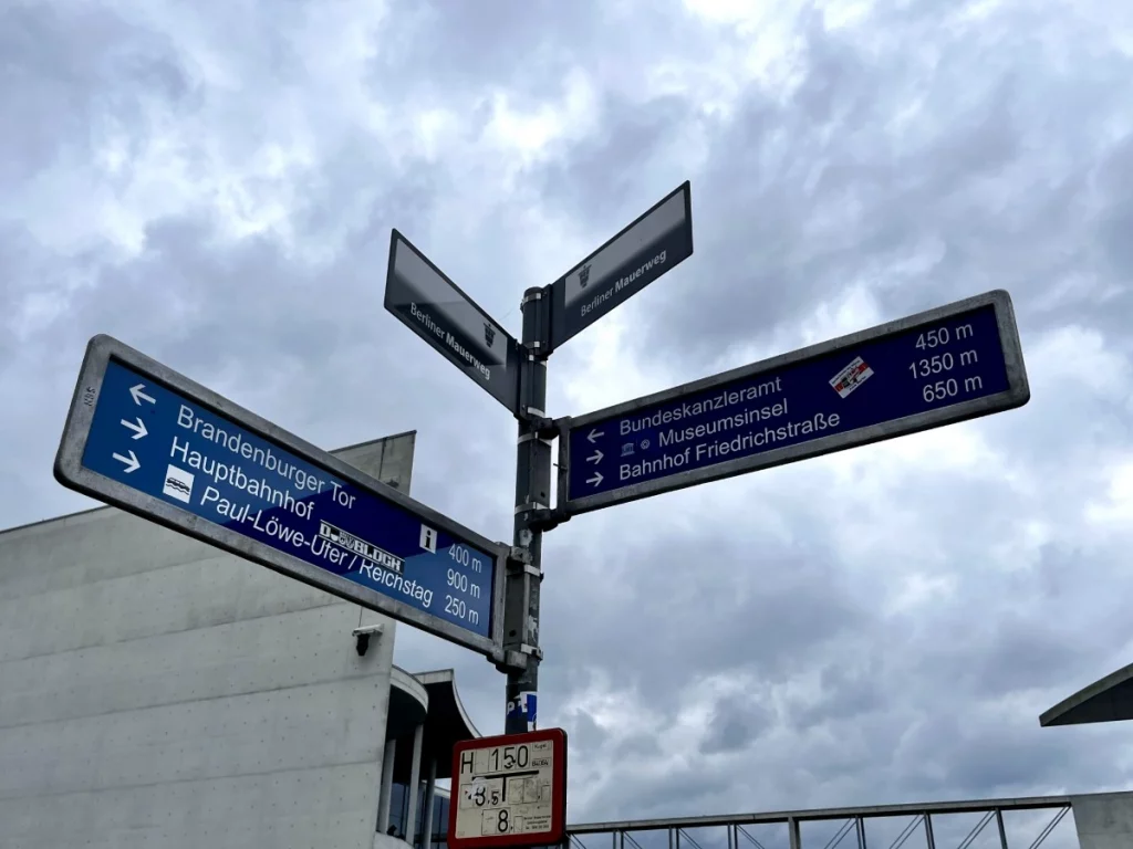 Alle Wege führen zum Ziel: Ein klassischer Berliner Wegweiser am Paul-Löbe-Ufer mit Entfernungsangaben zum Reichstag, Kanzleramt und Brandenburger Tor.