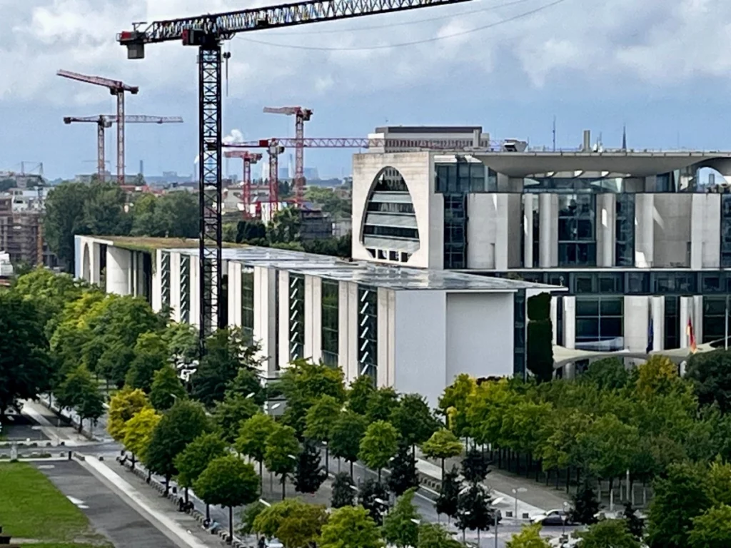 Berlin, die ewige Baustelle: Dieser Ausblick vom Reichstagsgebäude zeigt das Marie-Elisabeth-Lüders-Haus im Vordergrund und eine beeindruckende Anzahl an Baukränen am Horizont. Das Bild fängt die ständige Veränderung und das Wachstum der Hauptstadt perfekt ein – ein spannender Kontrast zwischen den bereits fertiggestellten, geradlinigen Regierungsbauten und den neuen Projekten, die im Hintergrund in den Himmel wachsen.