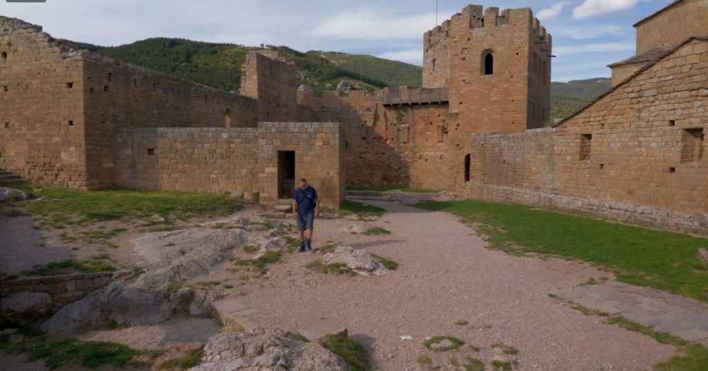 Ingo läuft durch den weitläufigen, von hohen Sandsteinmauern und einem quadratischen Wehrturm umgebenen Innenhof des Castillo de Loarre.