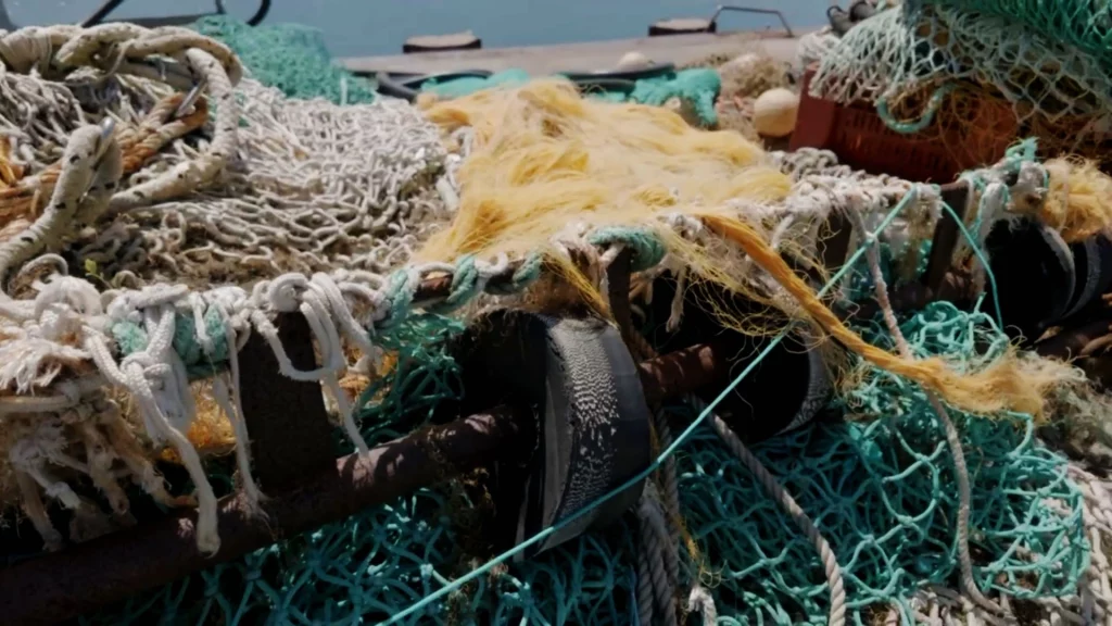 Nahaufnahme von bunten, übereinandergestapelten Fischernetzen und Seilen im Hafen an der Atlantikküste.