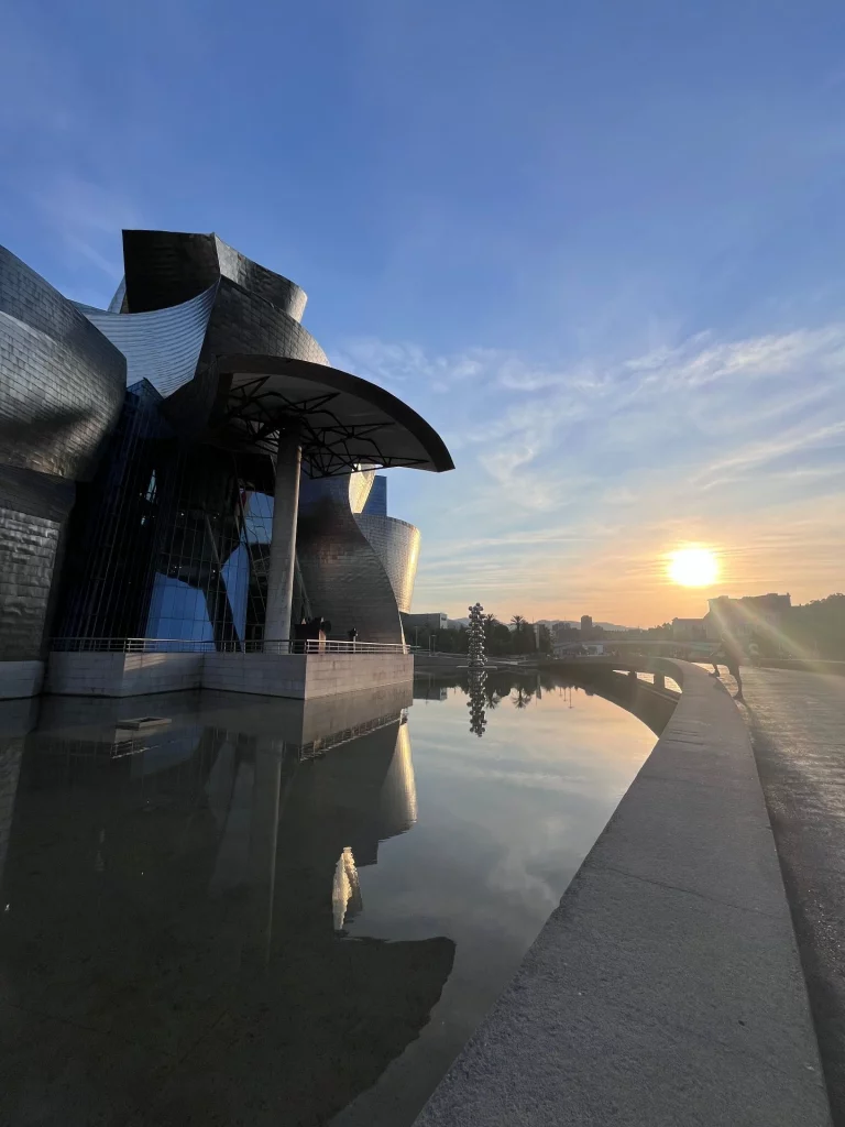 Nahaufnahme der geschwungenen, golden schimmernden Titanplatten des Guggenheim-Museums in Bilbao, die das warme Licht der Abendsonne reflektieren.