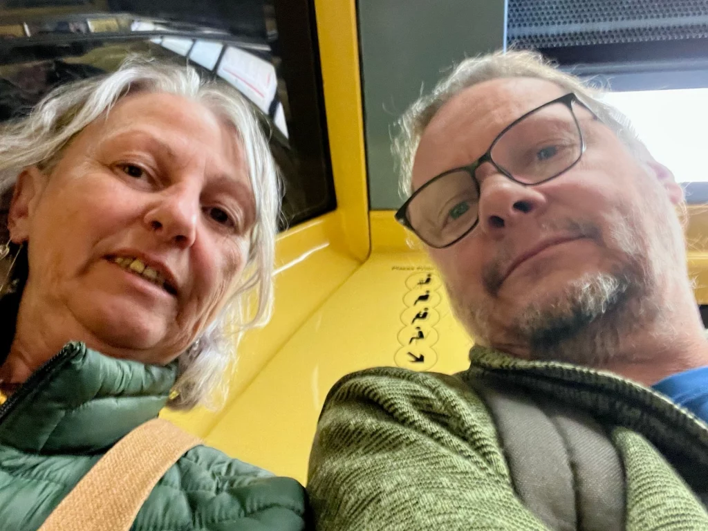 Karin und Ingo lächeln entspannt in die Kamera während einer Fahrt mit der gelben U-Bahn in Toulouse.